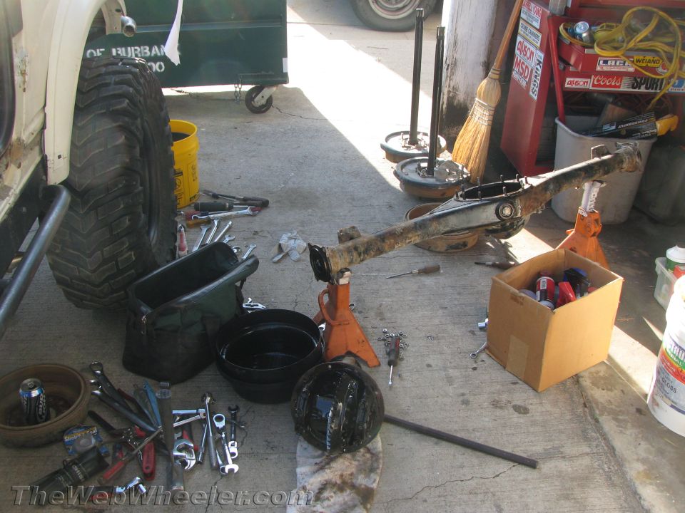 Vehicle axle on jack stands with tools scattered around