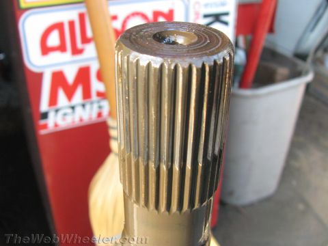 1987 Suzuki Samurai - A close-up view of a splined axle shaft, with a partial sign visible in the background.