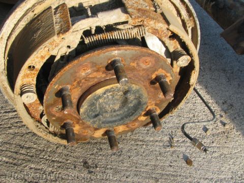 1987 Suzuki Samurai - A heavily rusted brake drum assembly is shown, with brake shoes and springs exposed.