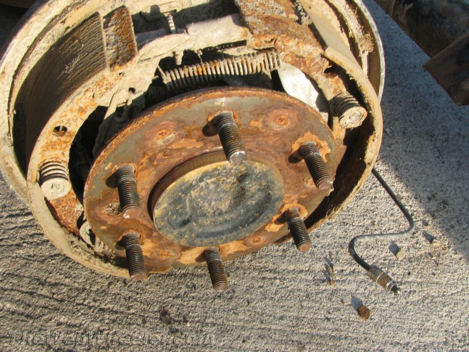 Rusty brake drum assembly with visible brake shoes and springs, on concrete