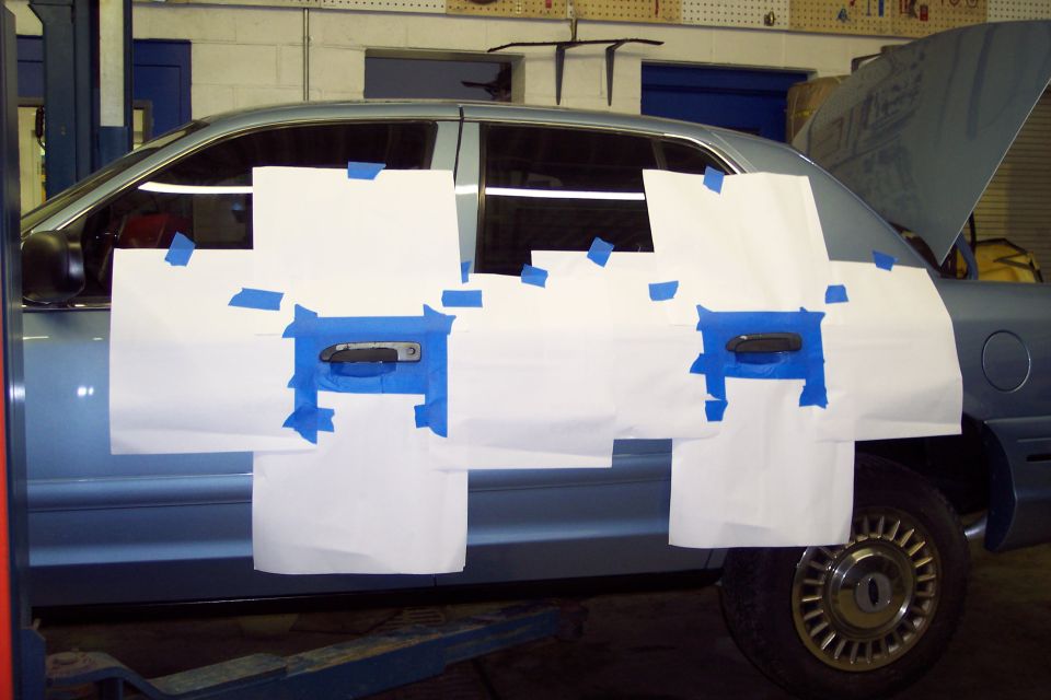 blue sedan, side view, door handles covered with paper and tape