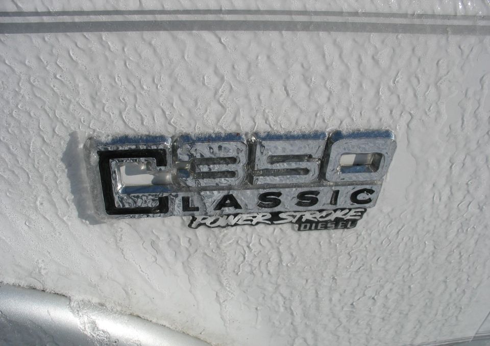 Ice-covered chrome C-350 Classic Power Stroke Diesel fender badge on white paint
