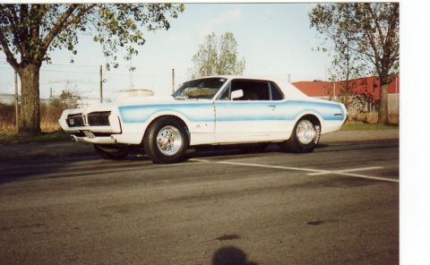 1998 Ford Crown Victoria - This modified 1968 Mercury Cougar features a prominent hood scoop and drag racing tires, indicating performance modifications.