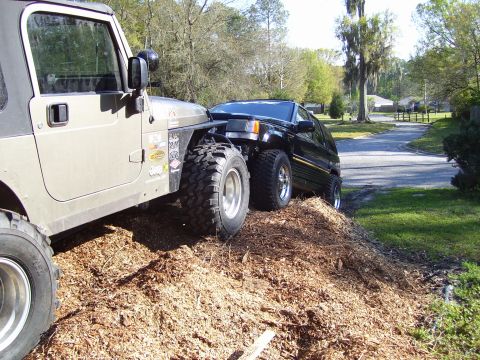 2004 Jeep TJ - A lifted Jeep Wrangler TJ is positioned closely to a Jeep Grand Cherokee ZJ, both appearing to be on an off-road course.