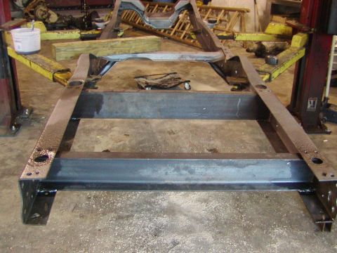 1991 Ford Bronco - A bare metal vehicle frame is shown on a concrete floor, likely in a repair shop.