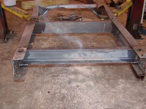 1991 Ford Bronco - A bare metal vehicle frame sits on a concrete floor, likely undergoing restoration or repair.