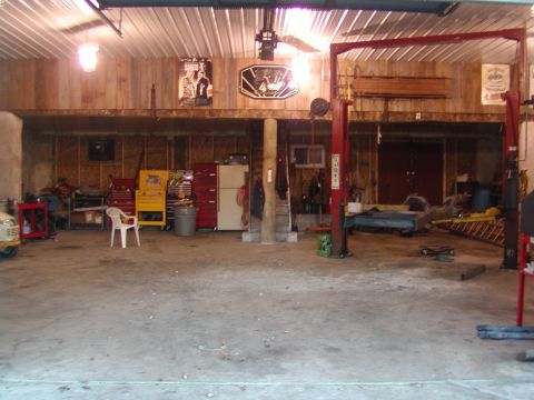 1991 Ford Bronco - A cluttered garage scene contains a car lift, various toolboxes, and storage shelves.