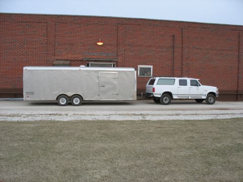 1995 Ford C-350 (Centurion Conversions) - A white 1995 Ford C-350 Centurion Conversions SUV is seen from the side, towing a large silver trailer.