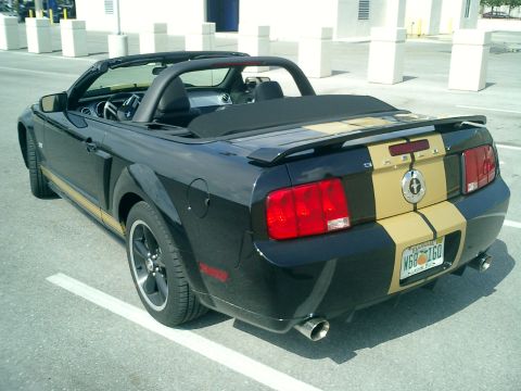 2007 Ford Mustang - Rear view of a black 2007 Ford Mustang convertible gold racing stripes and a spoiler.