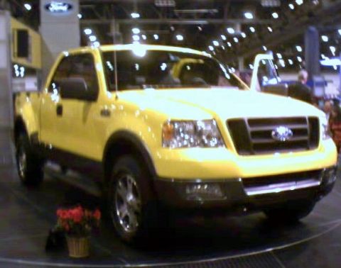 1981 Ford Bronco - This yellow Ford F-150 pickup truck is displayed indoors, possibly at a car show.