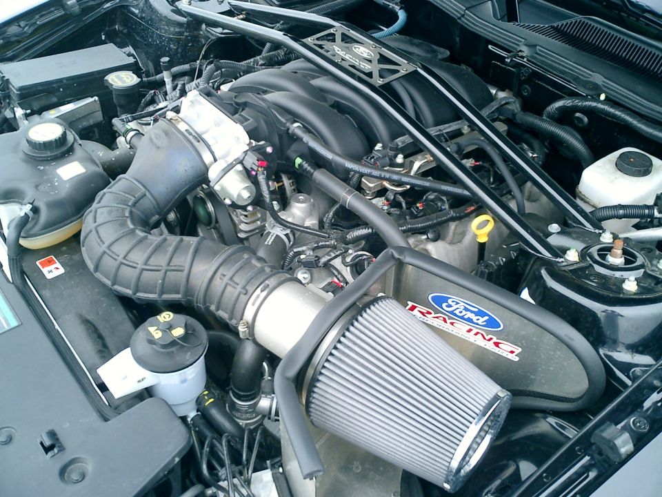 Engine bay with Ford Racing air filter and intake. Black engine cover with Ford Racing logo