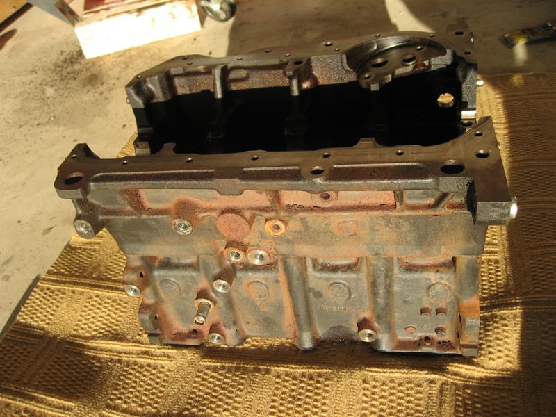 Bare engine block sitting on cardboard on a garage floor