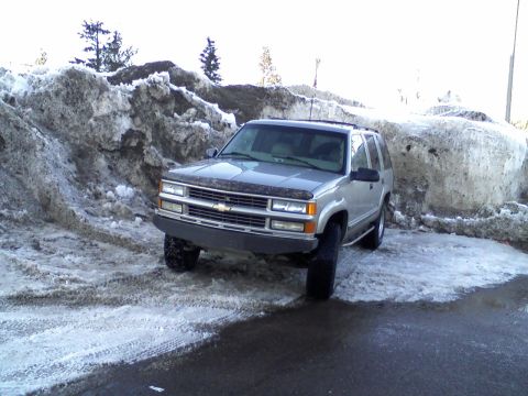 2000 Chevrolet Tahoe - This silver SUV is parked on an icy road, surrounded by large snow piles.