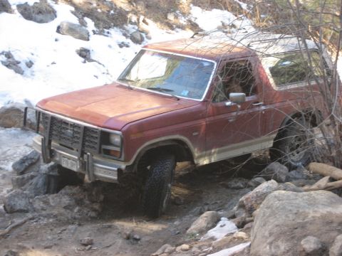 1986 Ford Bronco - This Ford Bronco is shown off-roading on a rocky, snow-dusted trail.