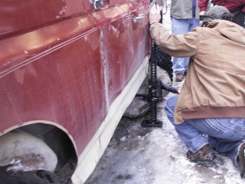 1986 Ford Bronco - A red 1986 Ford Bronco is being lifted with a hi-lift jack in a snowy environment.
