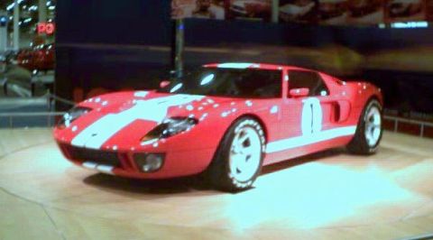 1981 Ford Bronco - A red Ford GT with white racing stripes is displayed indoors.