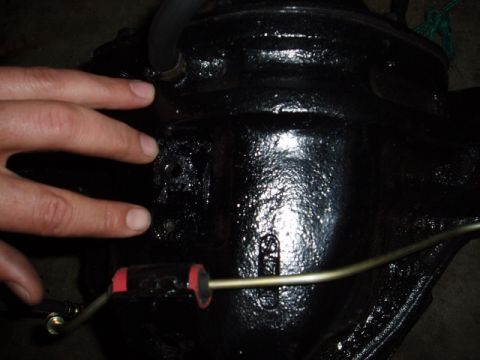 1980 Ford Bronco - A close-up view of a black differential housing, with a hand and brake line visible.