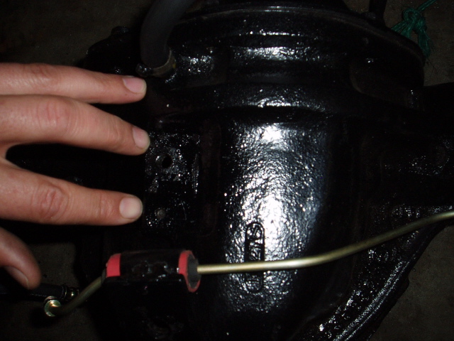 Black differential housing with a hand touching it and a brake line attached