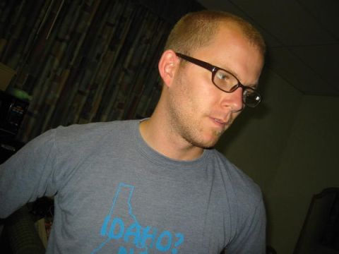 1996 Ford Bronco - A man with short hair and glasses looks down while wearing a gray t-shirt with a blue graphic of the state of Idaho.
