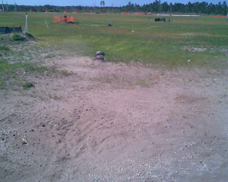 RC car kicking up dust on a dirt track, with construction fencing in the background