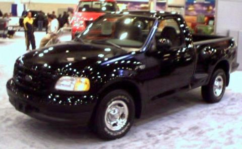 1981 Ford Bronco - A black pickup truck is displayed indoors, possibly at a car show.