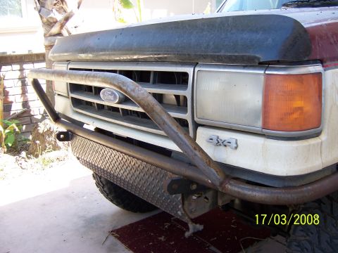 1991 Ford Bronco - Front view of a Ford truck a custom brush guard and diamond plate bumper, with a 4x4 badge visible.
