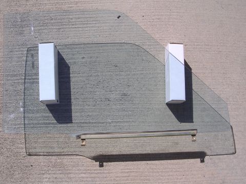 1983 Ferrari Enzo - Car door window glass, likely for a vintage vehicle, is shown laid flat on a concrete surface.
