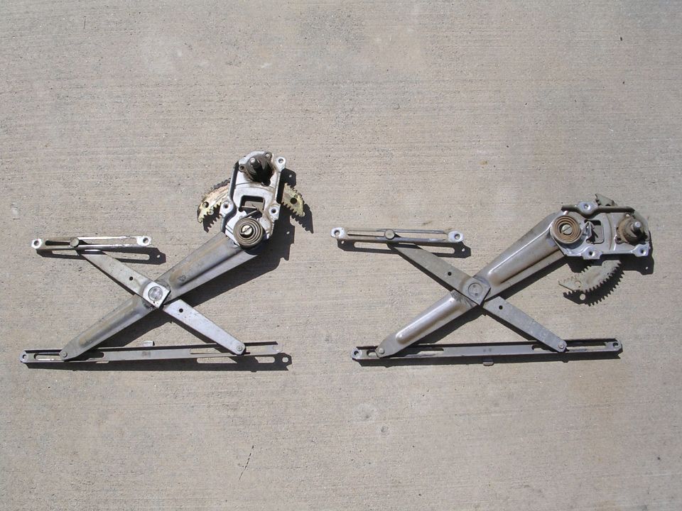 Pair of manual scissor window regulators laid out on concrete