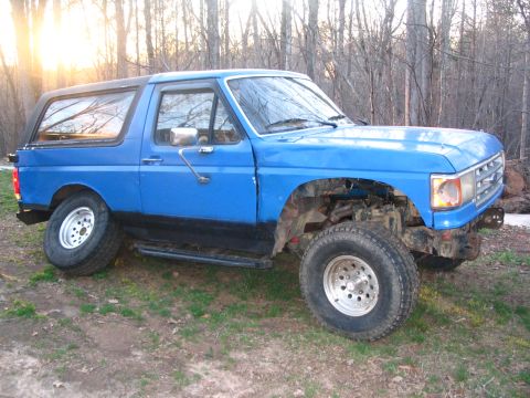 1987 Ford Bronco - Blue 1987 Ford Bronco shown in a three-quarter front view, parked outdoors.