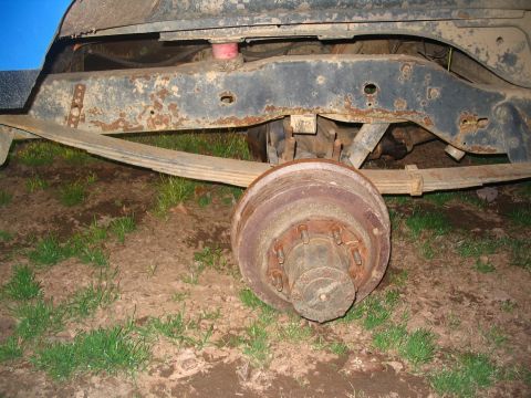 1987 Ford Bronco - Close-up of a vehicle's rear axle, drum brake, and leaf spring assembly.