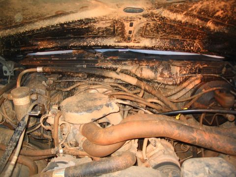 1987 Ford Bronco - The engine bay of this vehicle is heavily covered in mud, obscuring many details.
