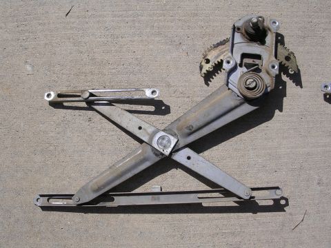 1983 Ferrari Enzo - Window regulator mechanism part shown on a concrete surface.