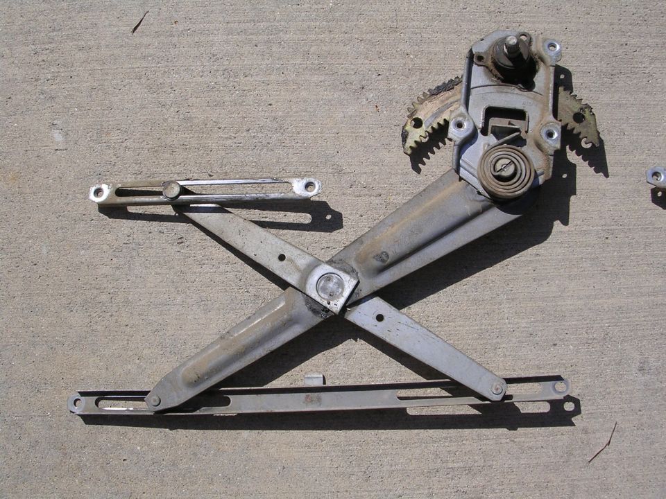 Window regulator mechanism with gears and spring, lying on concrete