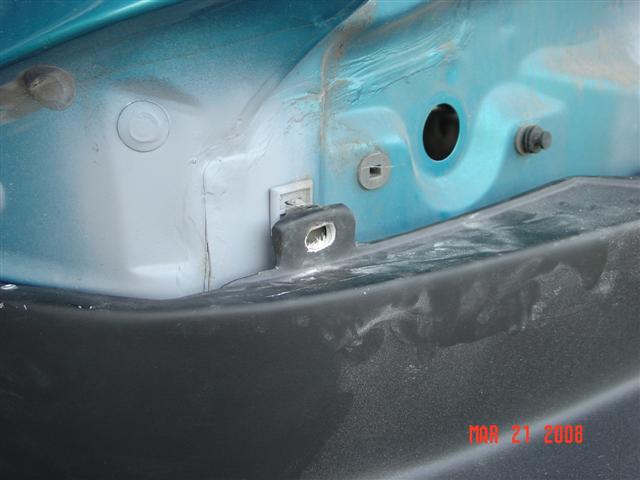 Teal car body panel with black bumper, showing mounting points and dust