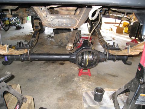 1996 Ford Bronco - Close-up view of a vehicle's rear axle assembly, differential, and suspension parts, likely undergoing maintenance or modification.