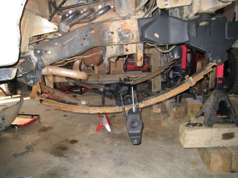 1996 Ford Bronco - The vehicle's undercarriage is visible, with suspension parts and leaf springs supported by jack stands.