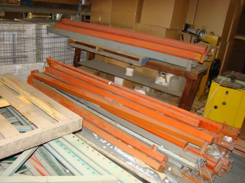 1989 Ford Bronco - Various industrial storage components, including metal beams and wooden pallets, are piled up in a warehouse setting.