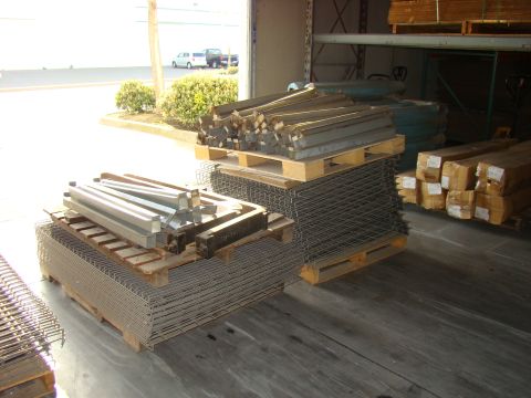 1989 Ford Bronco - Metal bars and mesh are stored on wooden pallets in a warehouse setting.