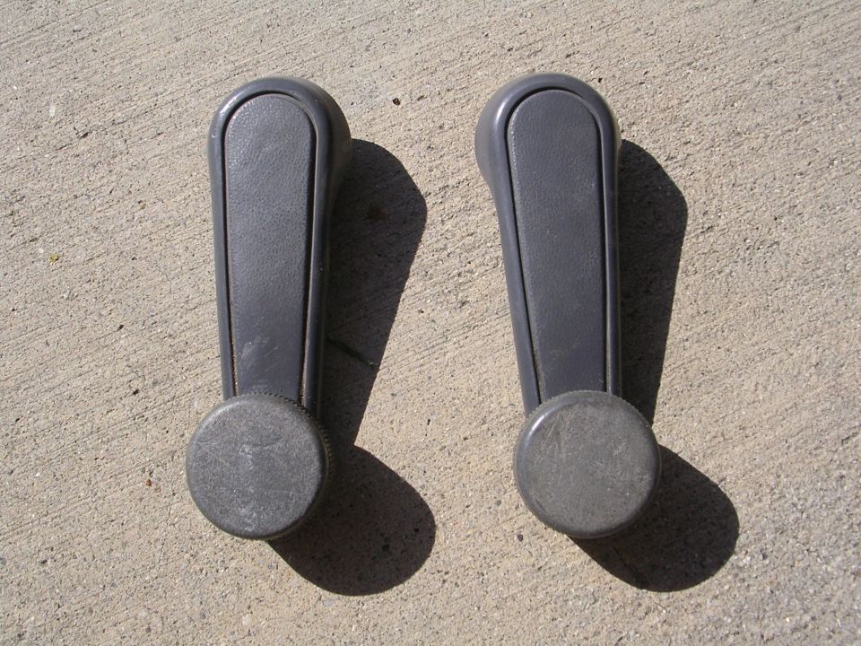 Pair of gray plastic manual window crank handles on concrete