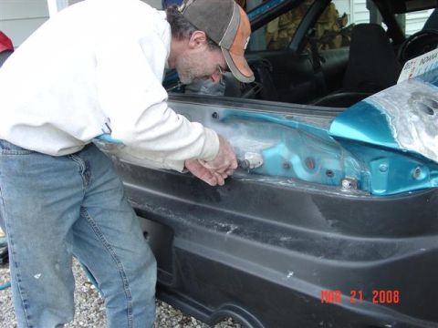1993 Ford Probe - Man works on the trunk area of a teal colored car. The interior and a license plate are visible.