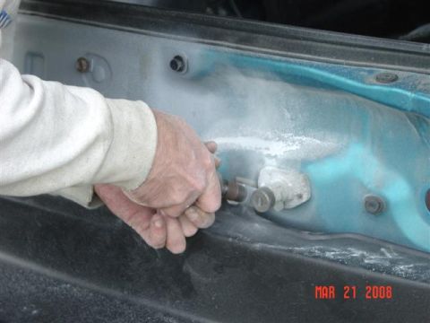 1993 Ford Probe - Close-up of a hand working on a car's inner fender area, with dust in the air.