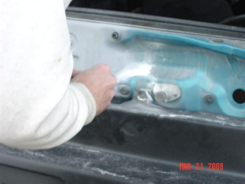 1993 Ford Probe - A person is shown working on the underside of a car's hood, applying filler to a section that has been painted blue.