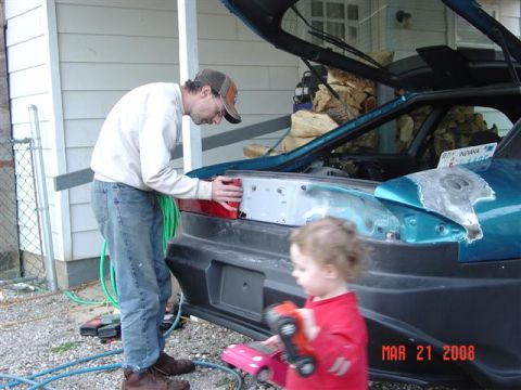 1993 Ford Probe - A man works on the taillight of a teal 1993 Ford Probe in a driveway.