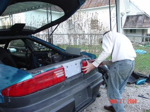 1993 Ford Probe - Man works on the rear of a teal 1993 Ford Probe with the trunk open.