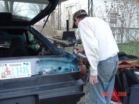 1993 Ford Probe - A person sprays paint into the trunk area of a car, with an Indiana license plate in view.