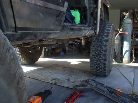 1994 Jeep Cherokee - Underbody view of a modified 1994 Jeep Cherokee, showing suspension and large tires, in a workshop.