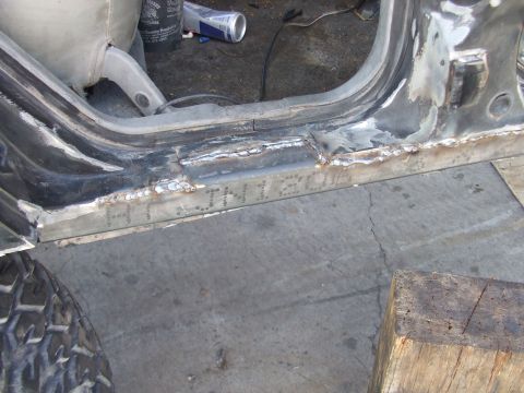 1994 Jeep Cherokee - Close-up view of a vehicle's rocker panel undergoing repair with visible welding and stamped markings.