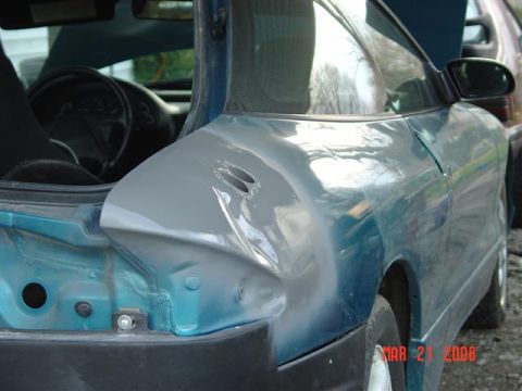 1993 Ford Probe - Repairing the rear quarter panel of a 1993 Ford Probe, with primer applied to damaged area.