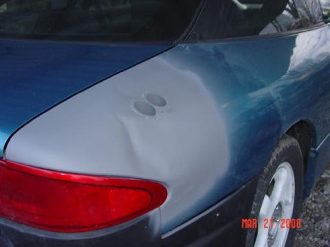 1993 Ford Probe - The rear quarter panel of a blue car shows primer, a dent, and two circular holes.