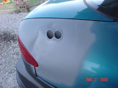 1993 Ford Probe - The rear of a teal car shows damage and two exhaust pipe openings.